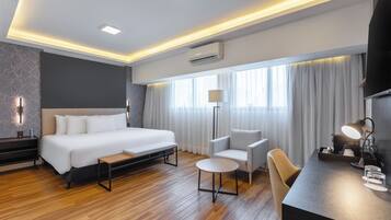 Una habitación de hotel moderna con una cama grande, mesita de noche, silla, escritorio y televisor de pantalla plana.