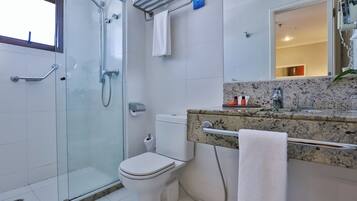 A modern bathroom with a glass shower enclosure, a toilet, and a granite countertop with a towel rack.
