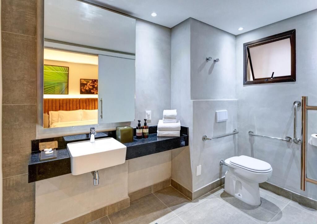 Un bagno moderno con lavandino, specchio, WC e zona doccia.