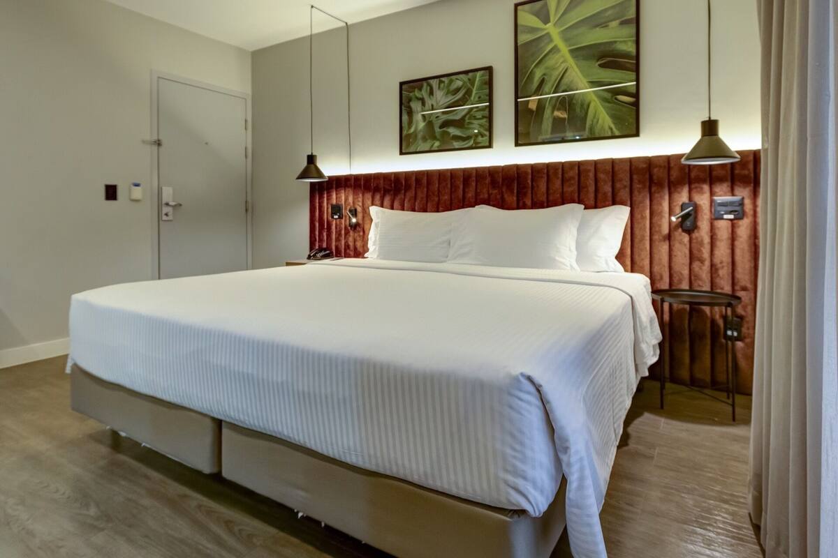 Ein großes Bett mit Holz-Kopfteil, ein Nachttisch und zwei Wandleuchten.