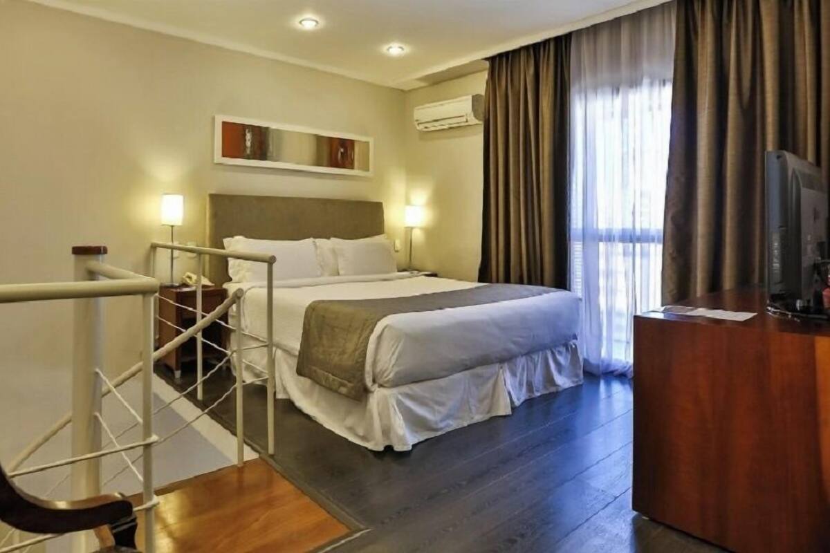 Ein Hotelzimmer mit Bett, Schreibtisch und Fernseher.