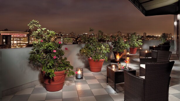 A rooftop terrace with potted plants, wicker furniture, and candles. - Melia Lima (Lima)