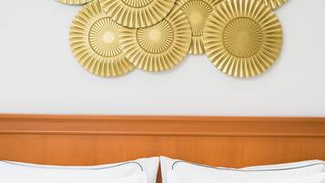 A hotel room with a wooden headboard, a white bed with two pillows, and a wall decorated with six gold-colored circular wall art pieces.