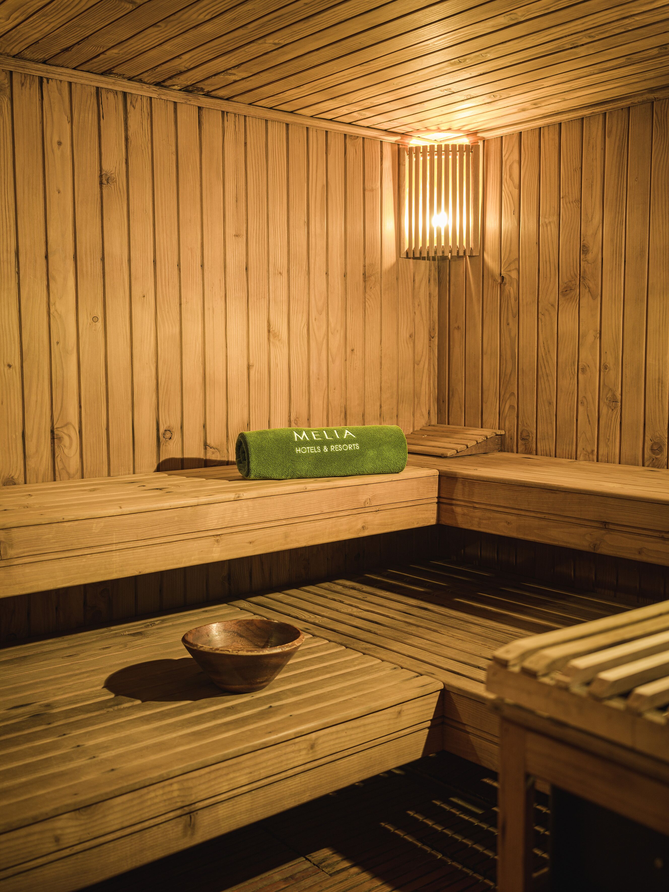 Una sauna de madera con bancos y una toalla con la etiqueta "MELIA HOTELS & RESORTS".