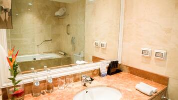 A bathroom with a marble sink, a glass vase with flowers, and a mirror reflecting the room.