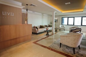 Un moderno vestíbulo de hotel con mostrador de recepción, zona de estar y grandes ventanales.