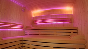 A wooden sauna with benches and pink lighting. - AKZENT Hotel Alpenrose (Nesselwang)