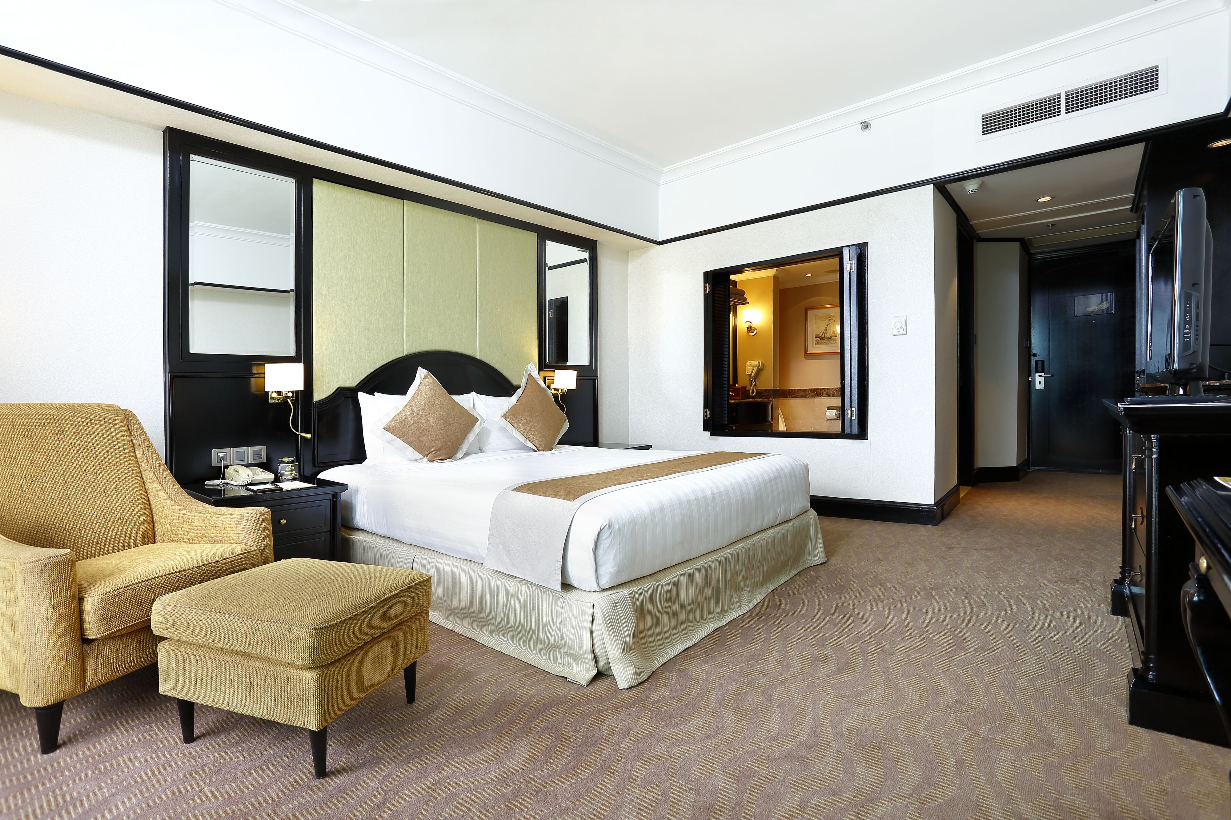 A hotel room with a bed, a chair, a desk, a television, and a mirror.