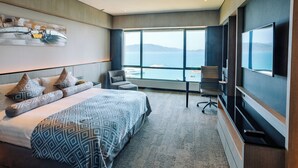 A modern hotel room with a large bed, a desk, a chair, and a TV. - The Pacific Sutera Hotel (Kota Kinabalu)