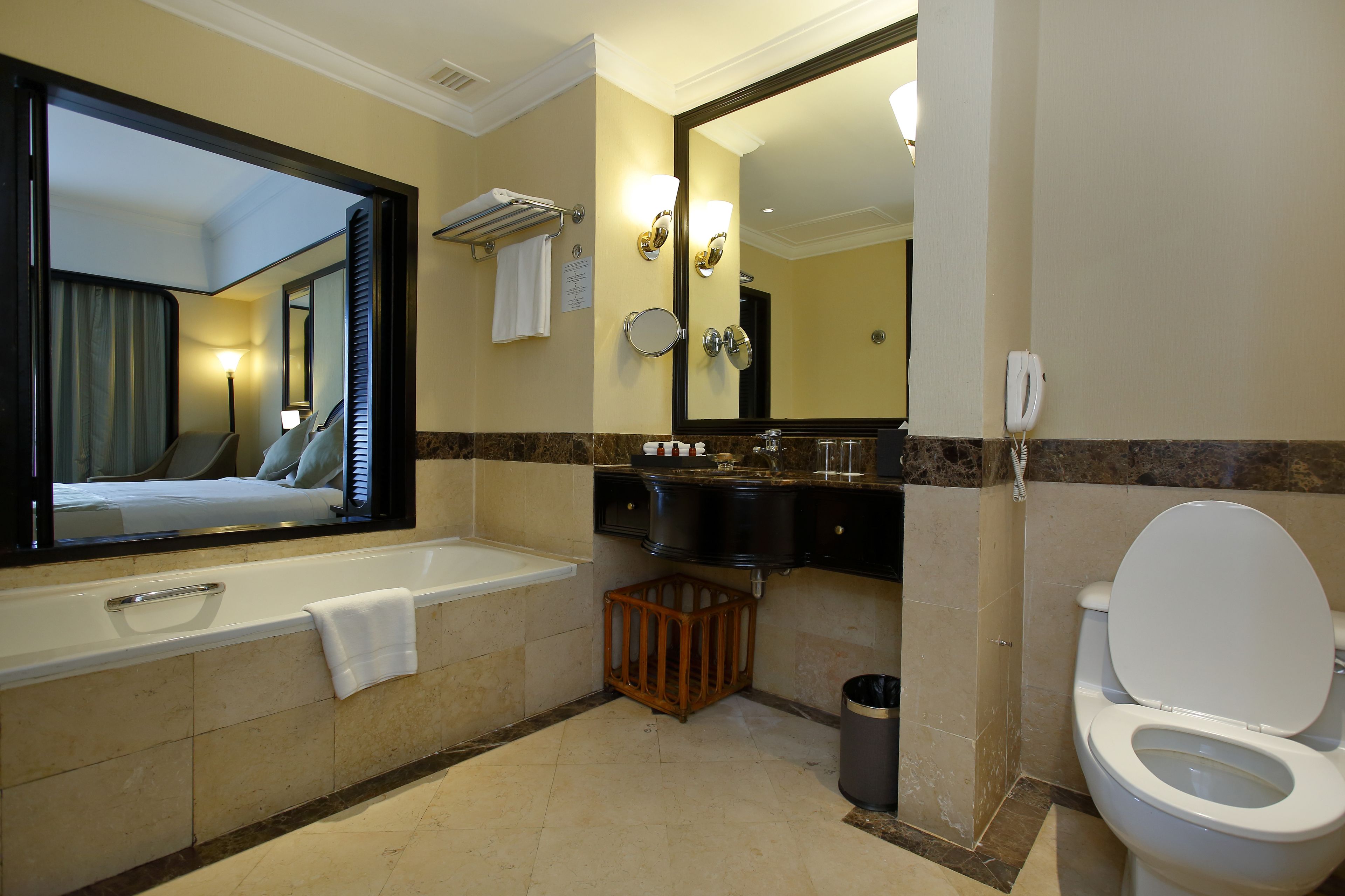 A modern bathroom with a large mirror, a bathtub, a toilet, and a sink.