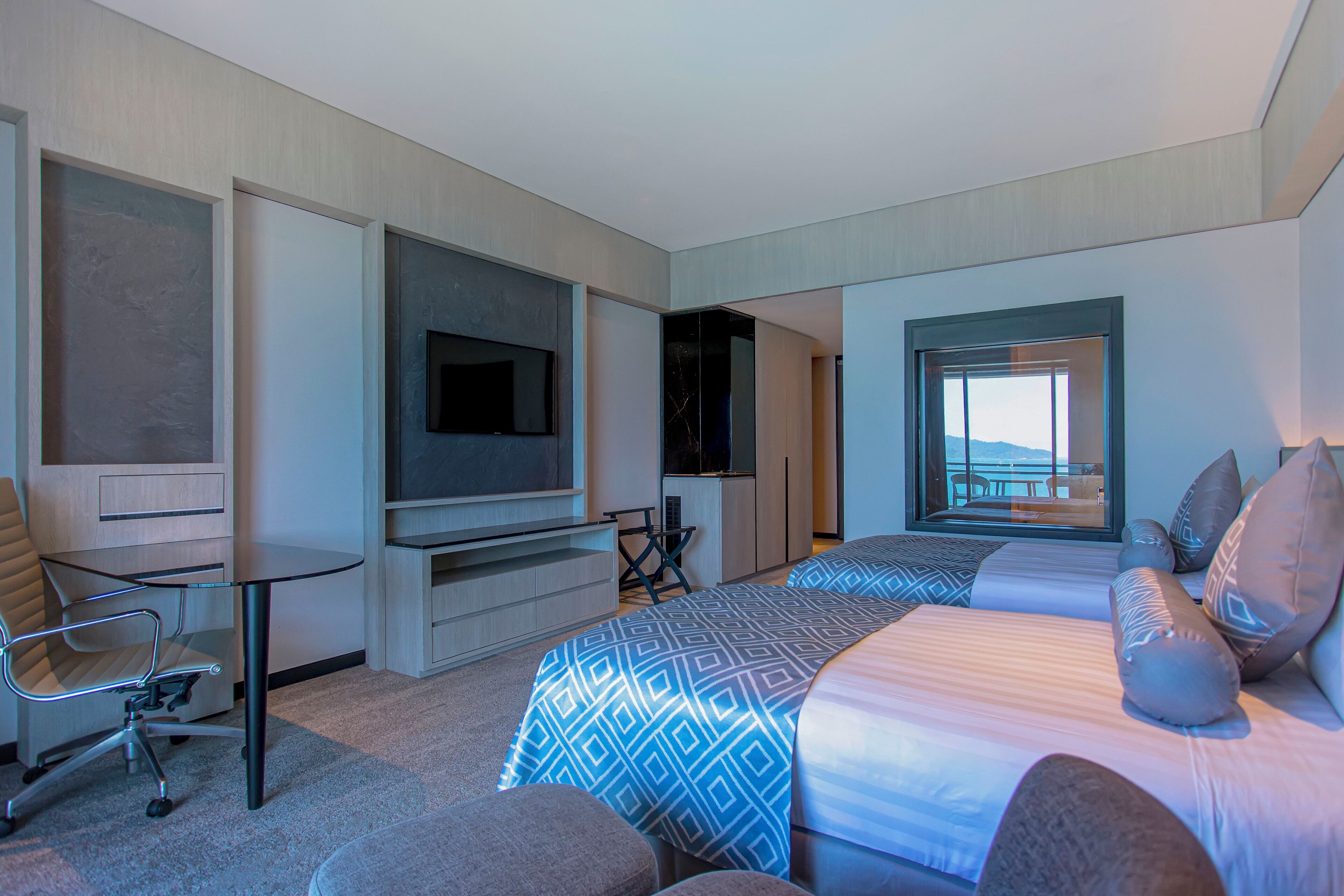 Une chambre d’hôtel moderne dotée d’un grand lit, d’un bureau, d’une télévision et d’un balcon avec vue.