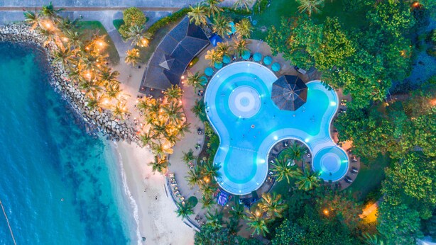 An aerial view of a resort with a large infinity pool, beach access, and palm trees. - The Pacific Sutera Hotel (Kota Kinabalu)