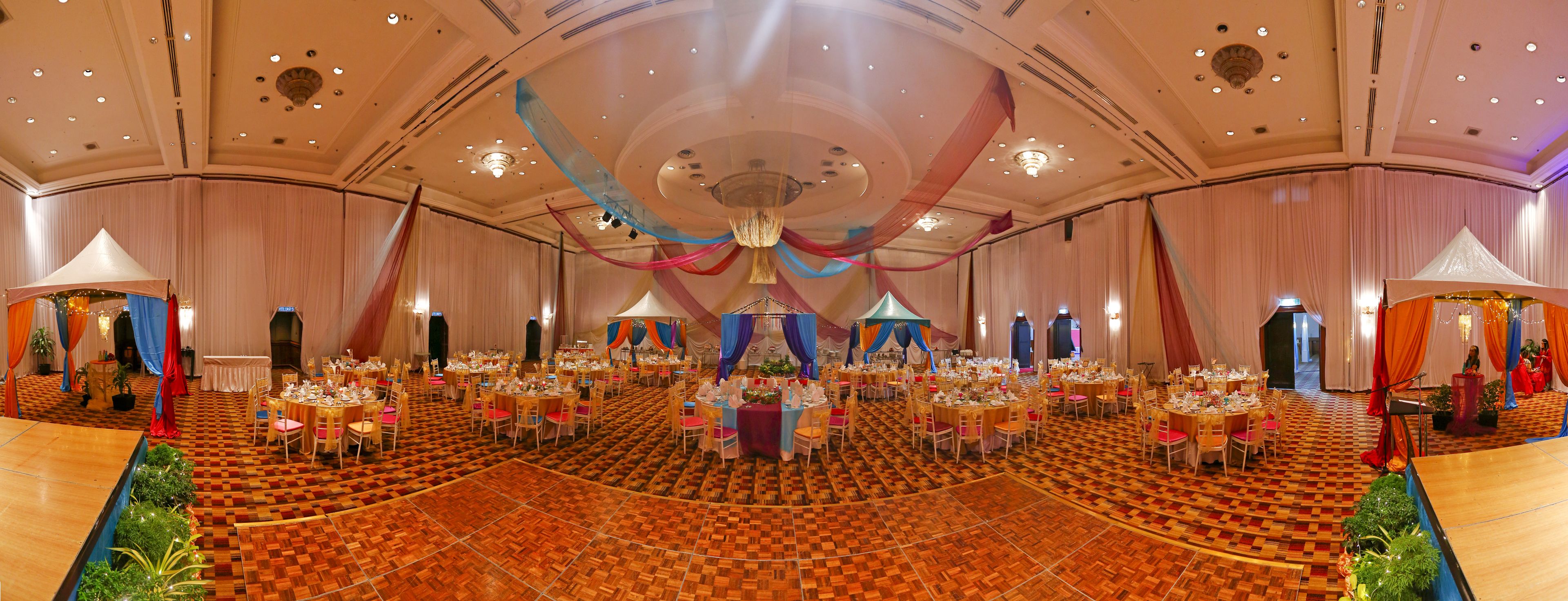 A large banquet hall with round tables, a checkered floor, and draped curtains.