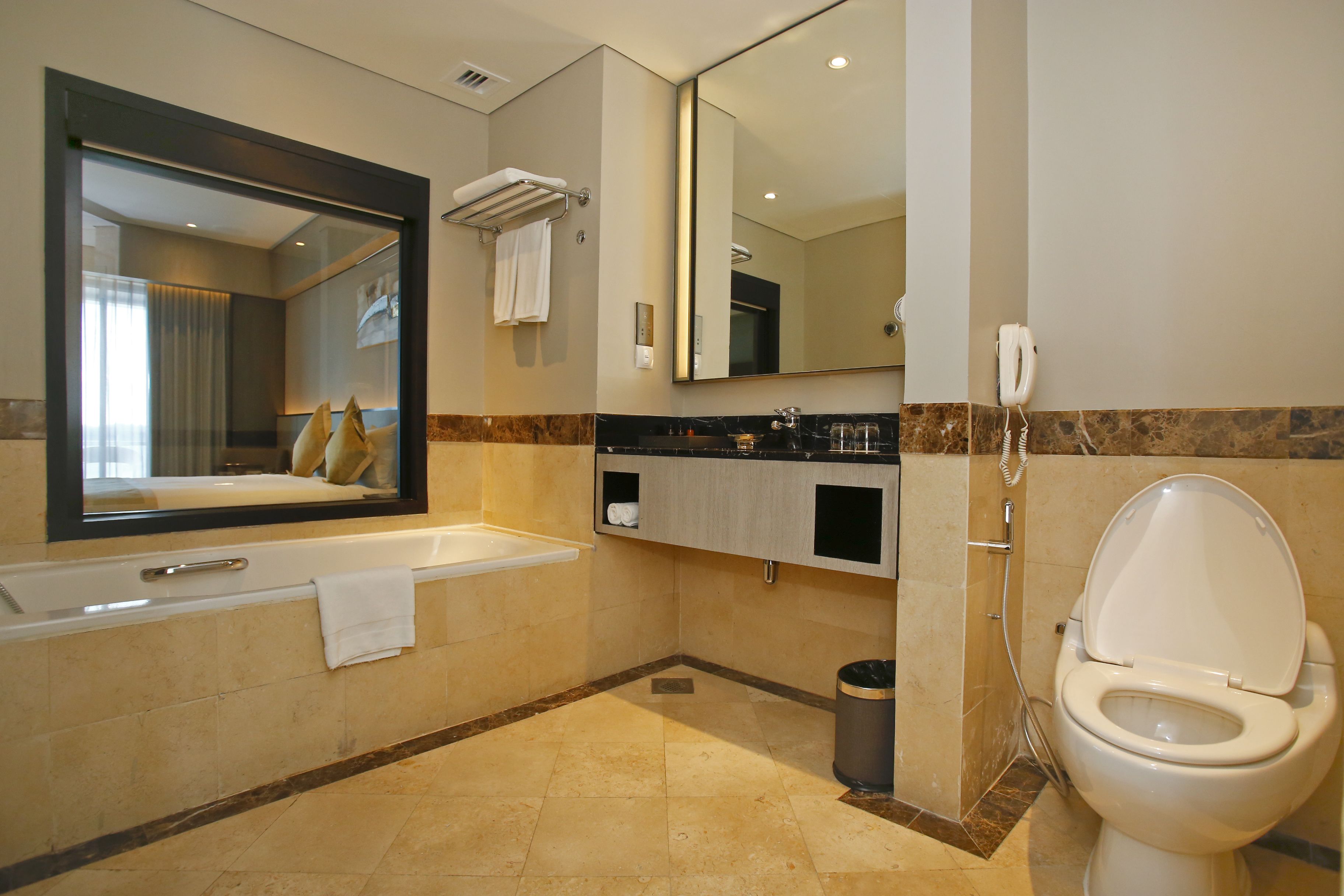 A modern bathroom with a large mirror, a bathtub, a toilet, and a shower.