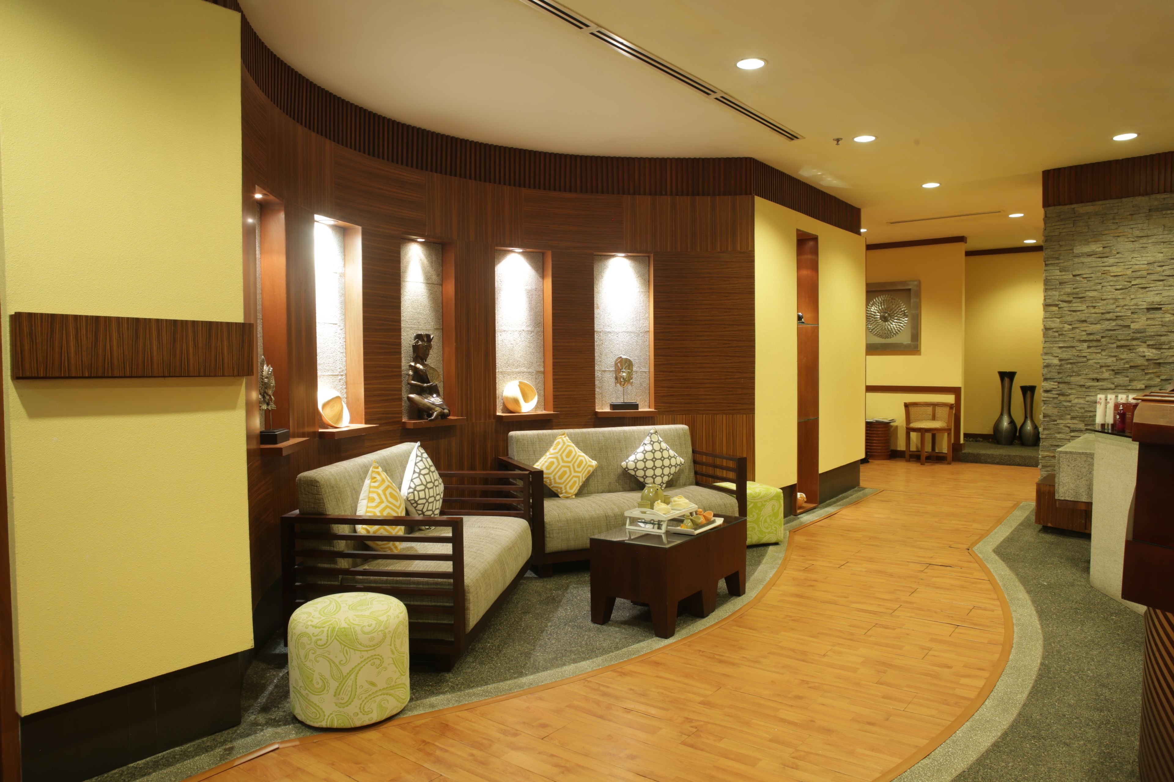 A modern lobby with a curved wooden floor, a sofa set, a coffee table, and a reception desk.