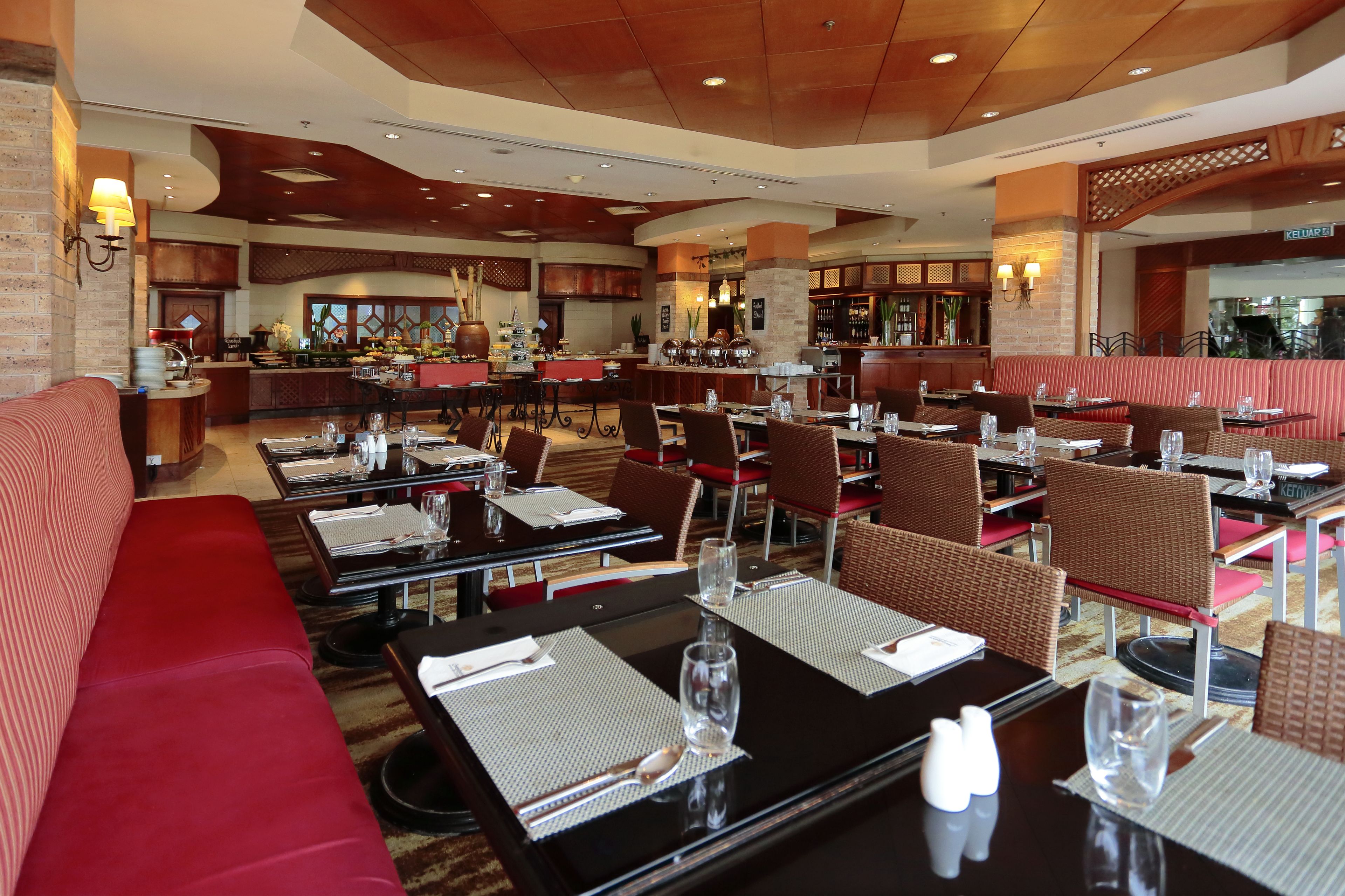 A restaurant with multiple dining tables and booths, equipped with place settings and glasses.