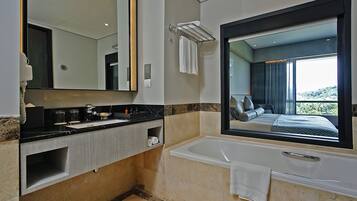 A modern bathroom with a large mirror, a bathtub, and a vanity with a sink and towel rack.