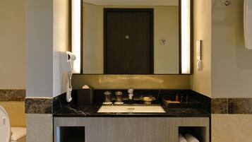A modern bathroom with a large mirror, a sink, a toilet, and a bathtub.