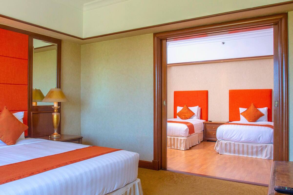 A hotel room with two beds, a large mirror, a lamp, and a television.