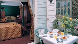 Una habitación con una cama, una mesa preparada para el desayuno y vistas a un edificio con ventanales de arco.