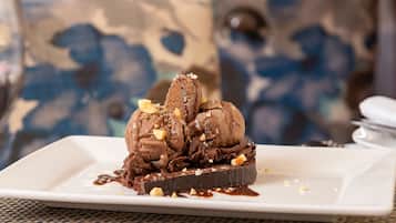 A dessert plate with chocolate ice cream and nuts on a white plate.