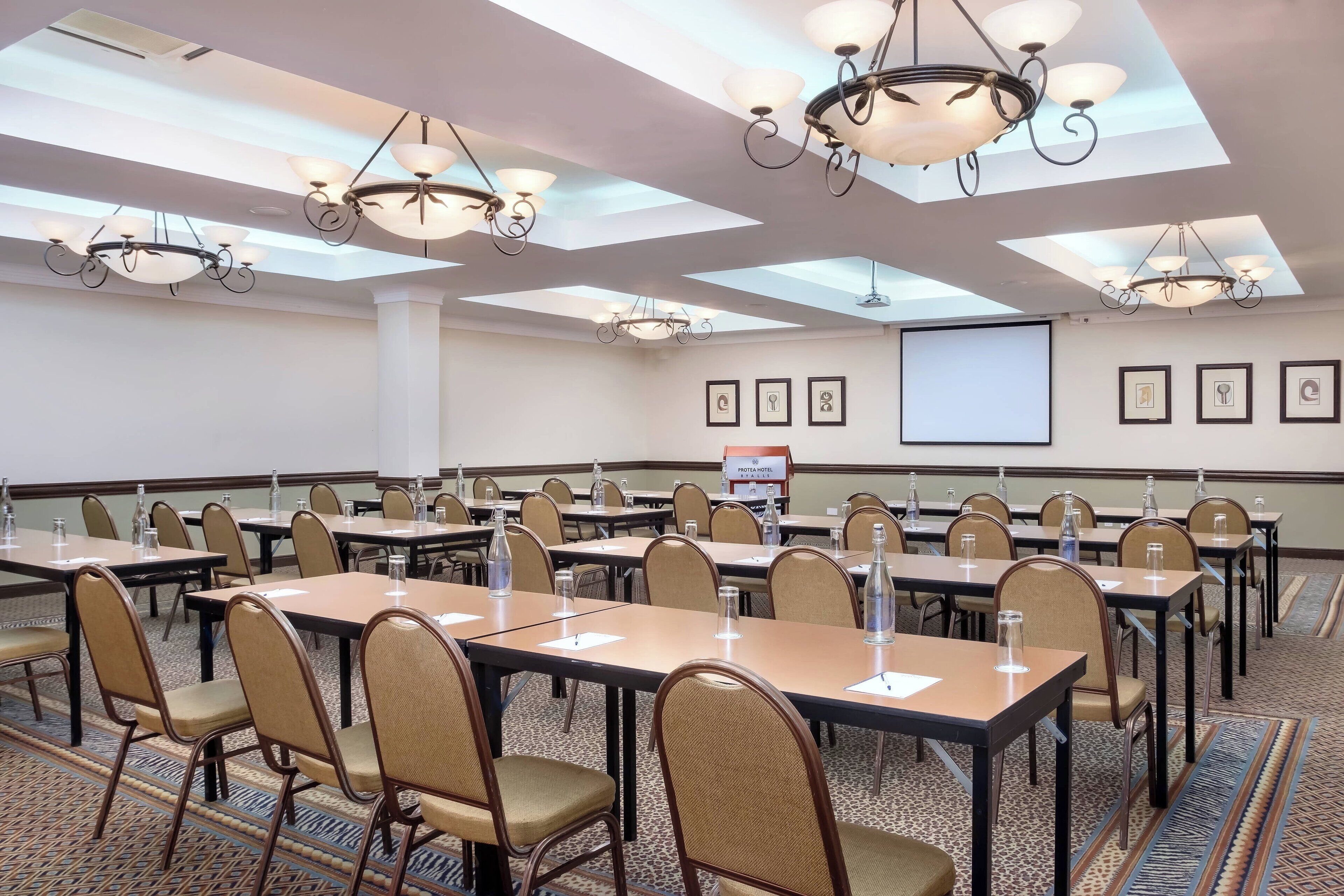 A conference room with tables, chairs, and a projector screen.
