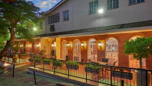 A building with a white facade, arched windows, and outdoor seating with planters.