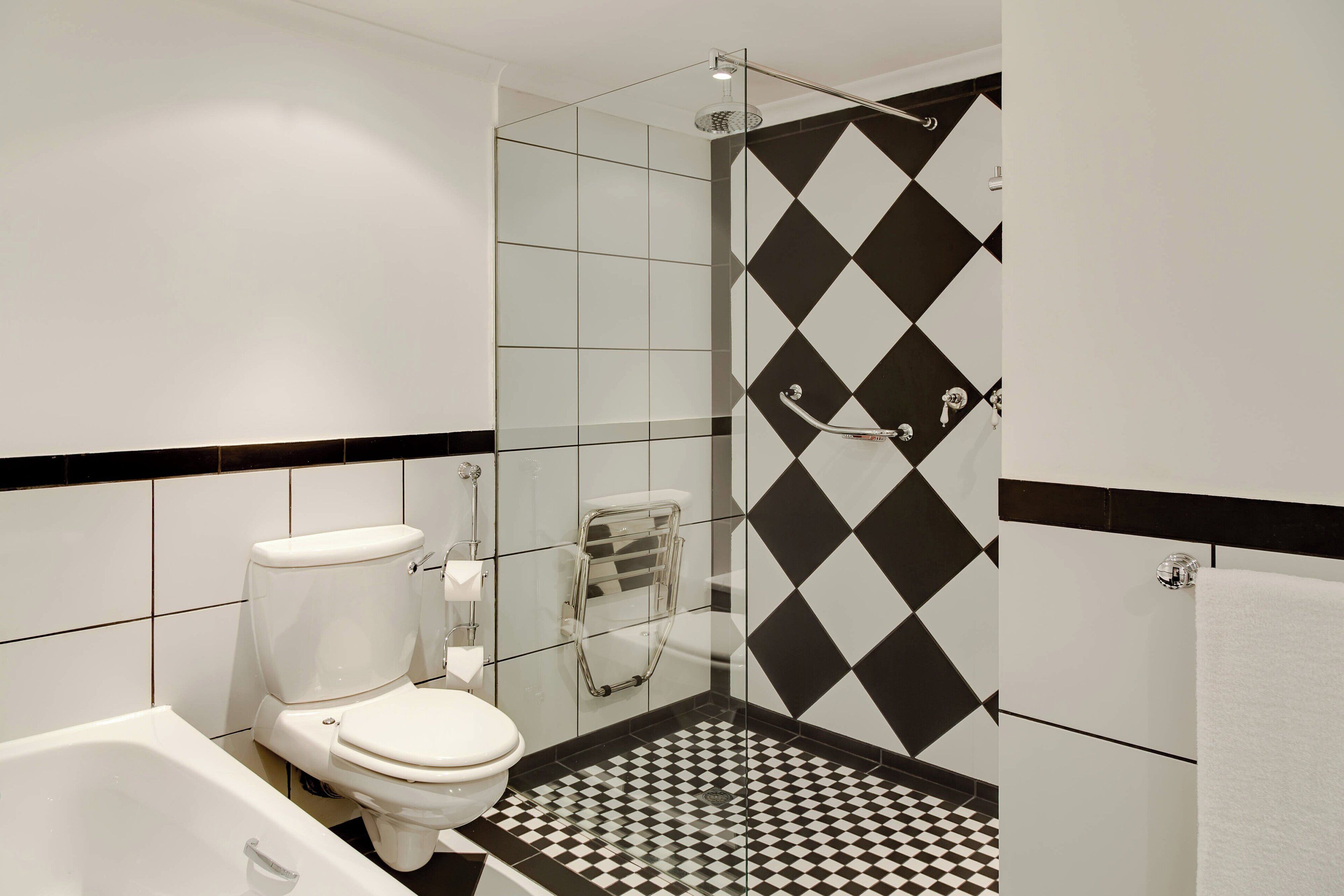 A bathroom with a black and white checkered floor, a white toilet, and a glass-enclosed shower.