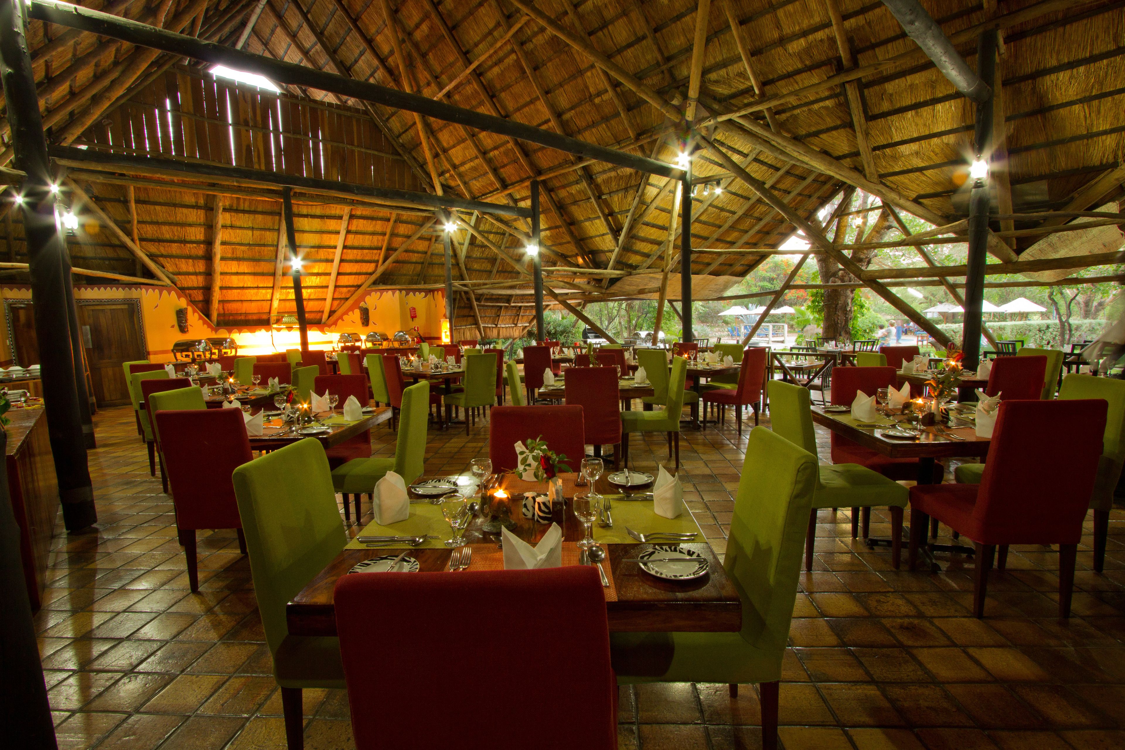 Un restaurant doté de nombreuses tables et chaises, d’un toit de chaume élevé et d’un sol carrelé.