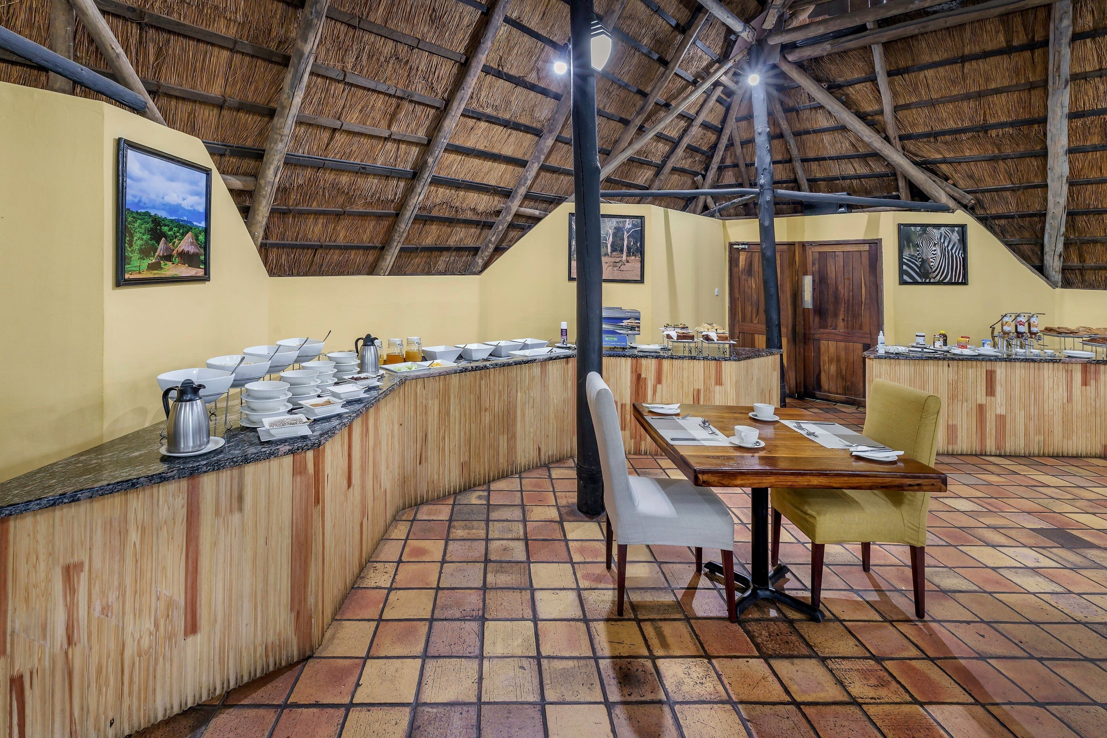 Un restaurante con techo de paja, mostrador de madera y suelo de baldosas.