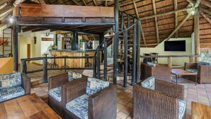Un intérieur rustique avec des meubles en osier, un escalier en bois et un coin bar.