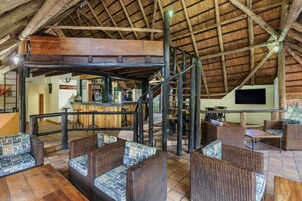 A rustic interior with wicker furniture, a wooden staircase, and a bar area.