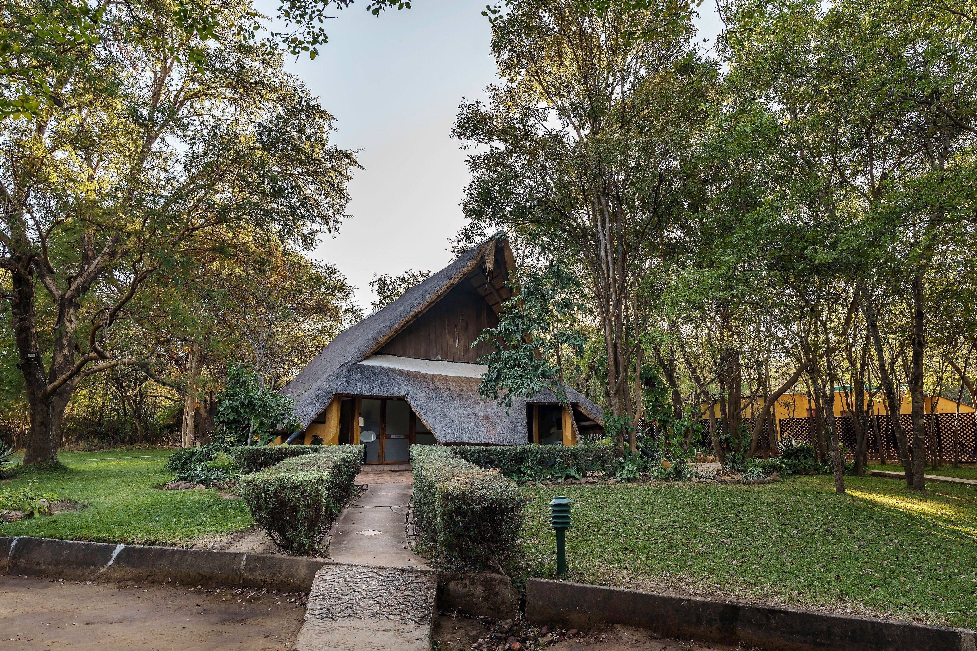 A rustic building with a sloped roof, surrounded by a well-maintained garden and trees.