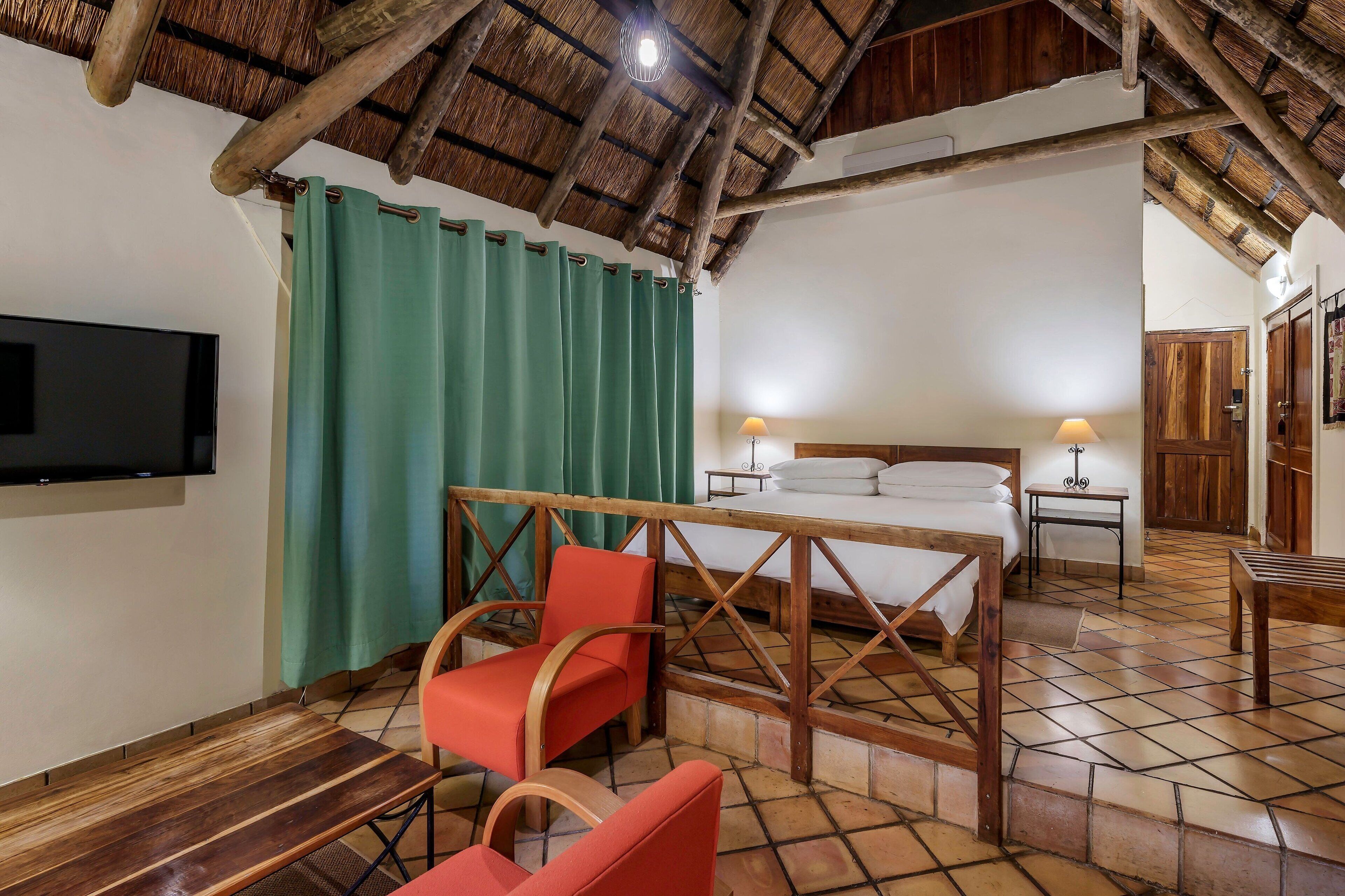 Quarto com cama, televisão, mesa e cadeira.