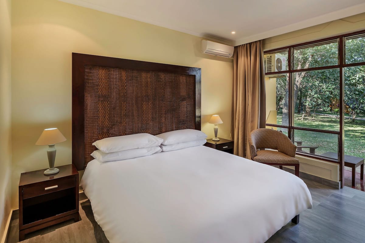 A neatly made bed with white linens, a wooden headboard, and two bedside tables with lamps.
