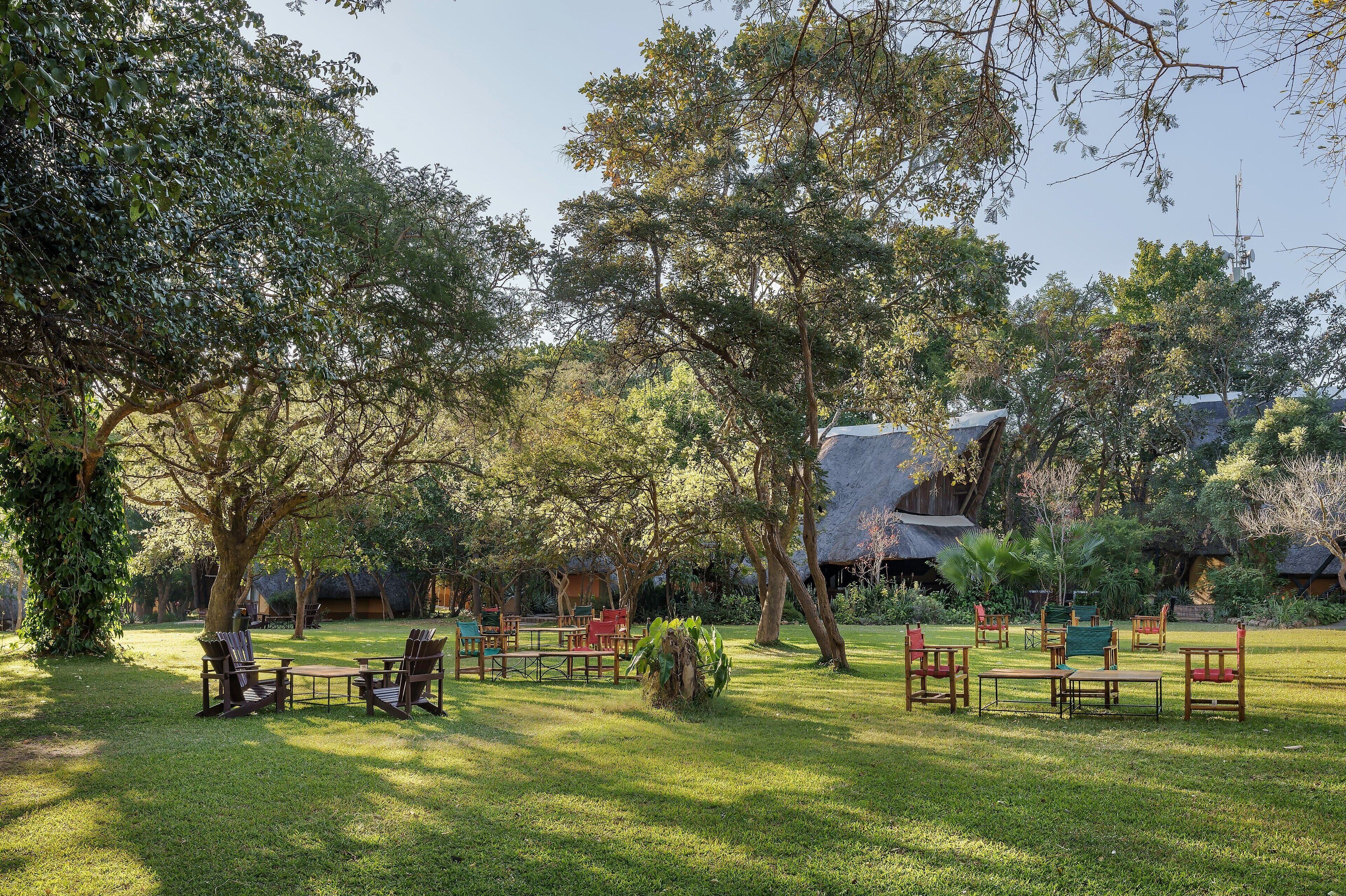 A lush garden with outdoor seating and thatched-roof structures.