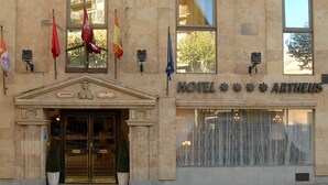 Un edificio con fachada clásica, un letrero que dice "HOTEL ARTHEUS" y varias banderas.