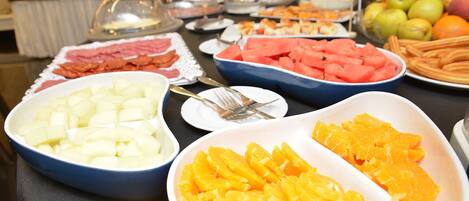Un bufé con diversas opciones de comida, incluyendo frutas y verduras.