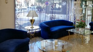 Una sala de estar moderna con un sofá azul, una mesa de centro de vidrio y una araña.
