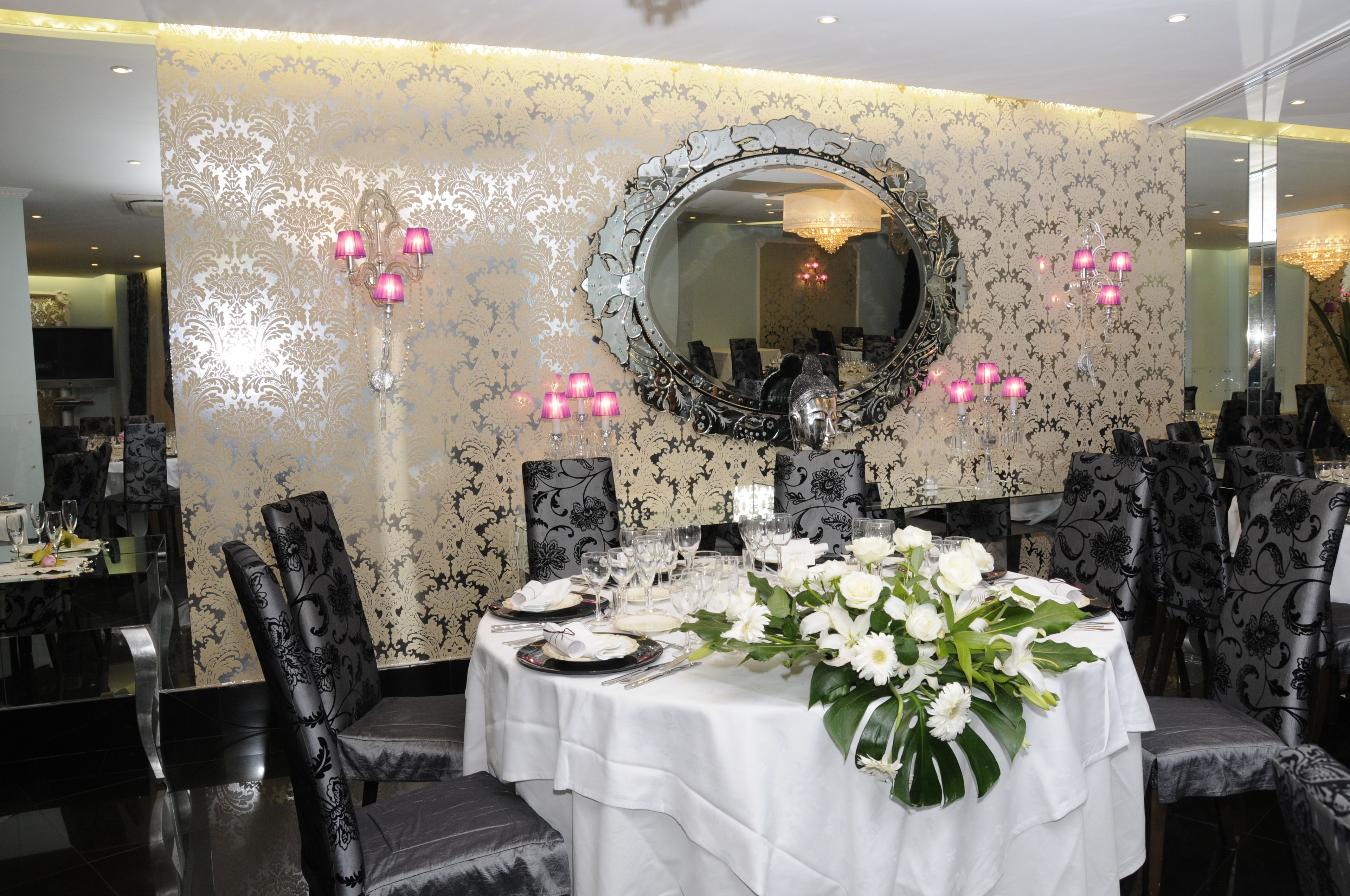 A dining area with a round table set for a meal, surrounded by chairs with a patterned upholstery.