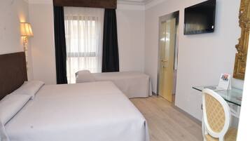 Une chambre d’hôtel avec deux lits, un bureau avec une chaise, une télévision et une porte.