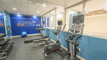A gym with treadmills, an elliptical, and dumbbells.