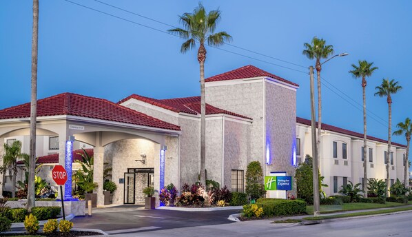 A hotel with a red-tiled roof, a stop sign, and a Holiday Inn Express sign.