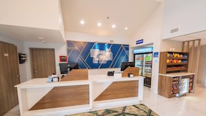 A reception area with a modern design, including a reception desk, a digital display, and a refrigerator stocked with beverages. - Holiday Inn Express St. Augustine near Dtwn - Historic by IHG (St. Augustine)