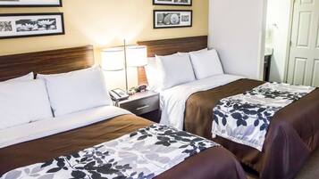 Une chambre d’hôtel avec deux lits, une table de chevet avec une lampe et des tableaux encadrés au mur.