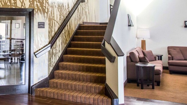 A staircase with a handrail leading to a second floor, a seating area with two sofas and a table, and a wall with a patterned design. - Sleep Inn Tinley Park I-80 near Amphitheatre-Convention Center (Tinley Park)