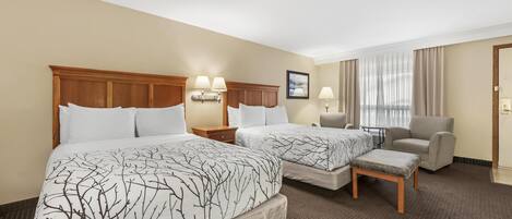 A hotel room with two beds, a chair, a small table, and a nightstand.