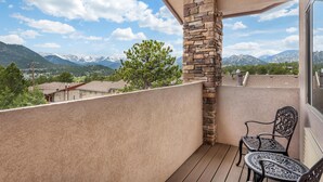 A balcony with a stone pillar, two chairs, and a view of mountains. - Best Western Plus Silver Saddle Inn (Estes Park)