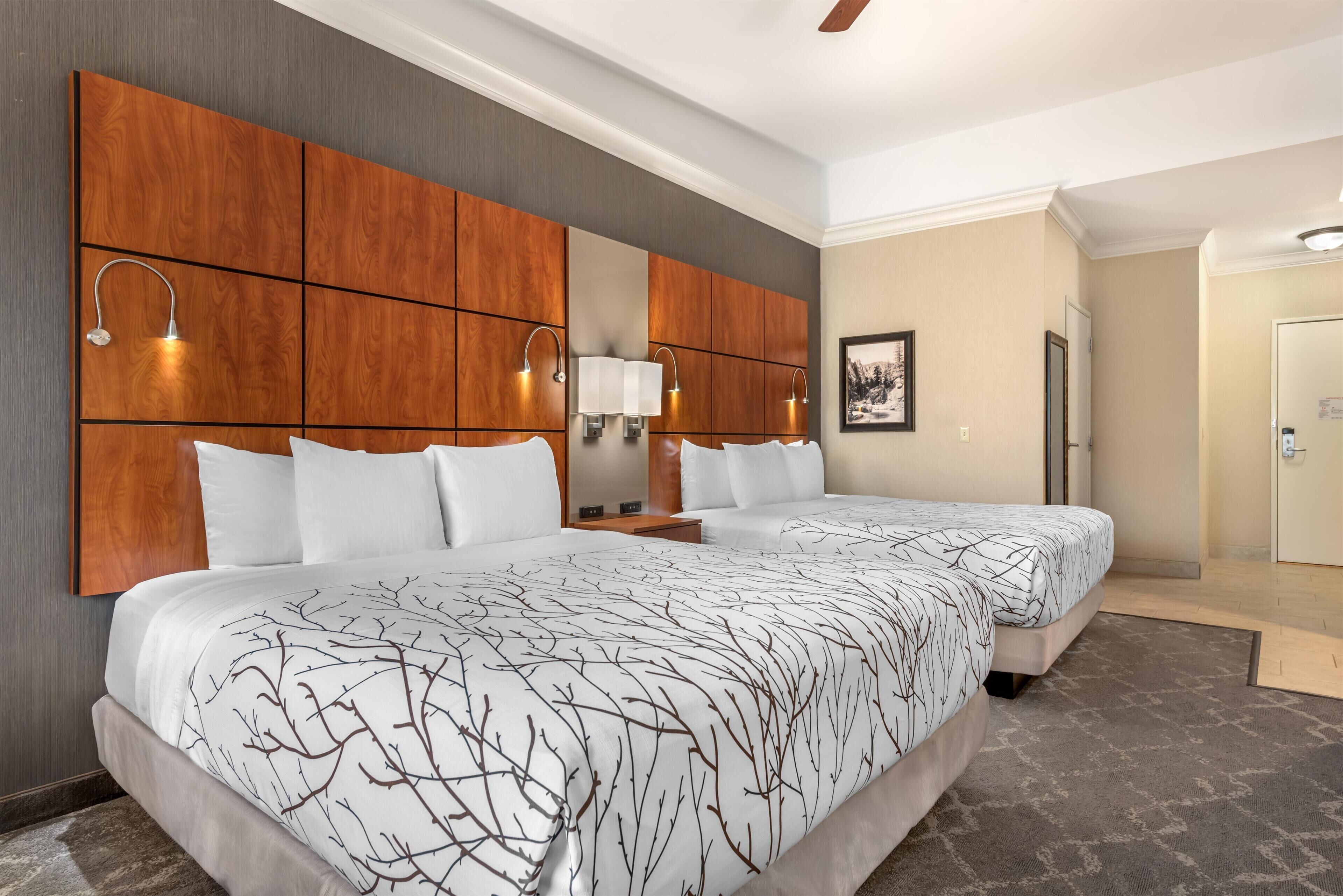 Una habitación de hotel con una cama grande, un cabecero de madera y una mesita de noche.