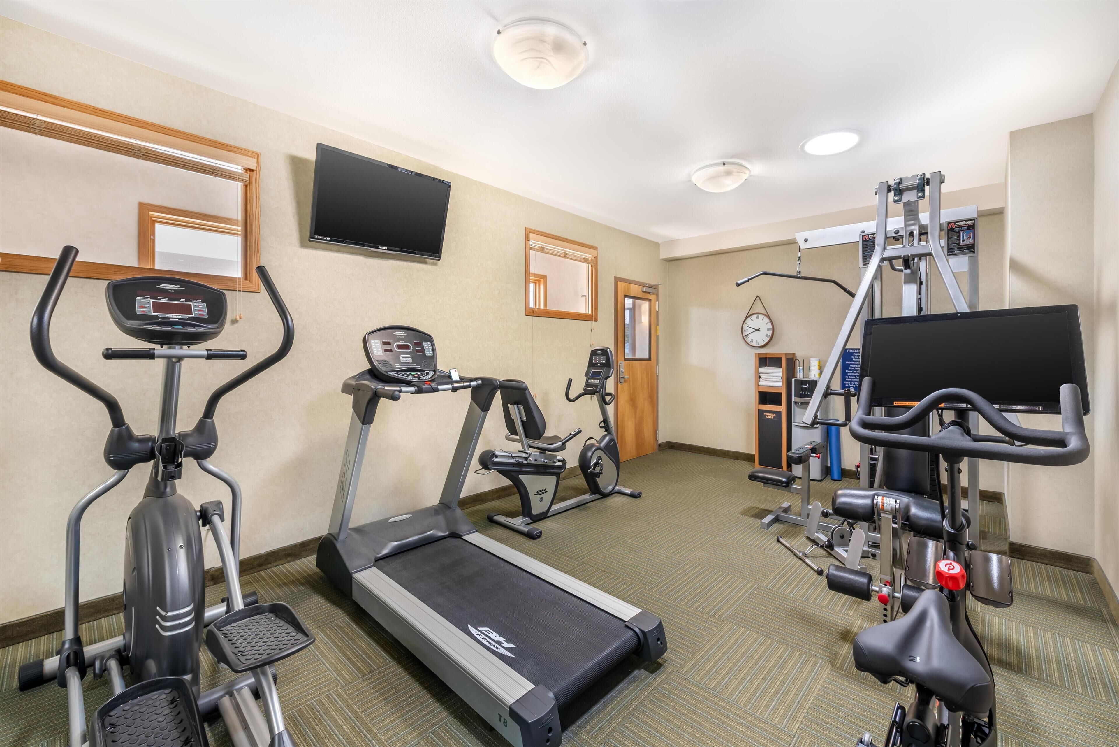 Een hotel fitnessruimte met loopbanden, elliptische trainers en gewichtstoestellen.